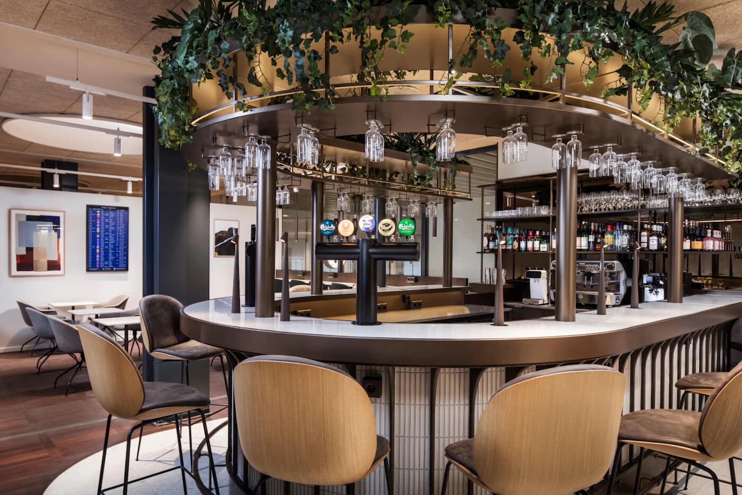 Runder Tresen mit Barhockern, Zapfsäulen und hängenden Gläsern in der Aspire Lounge Terminal 2 am Flughafen Kopenhagen