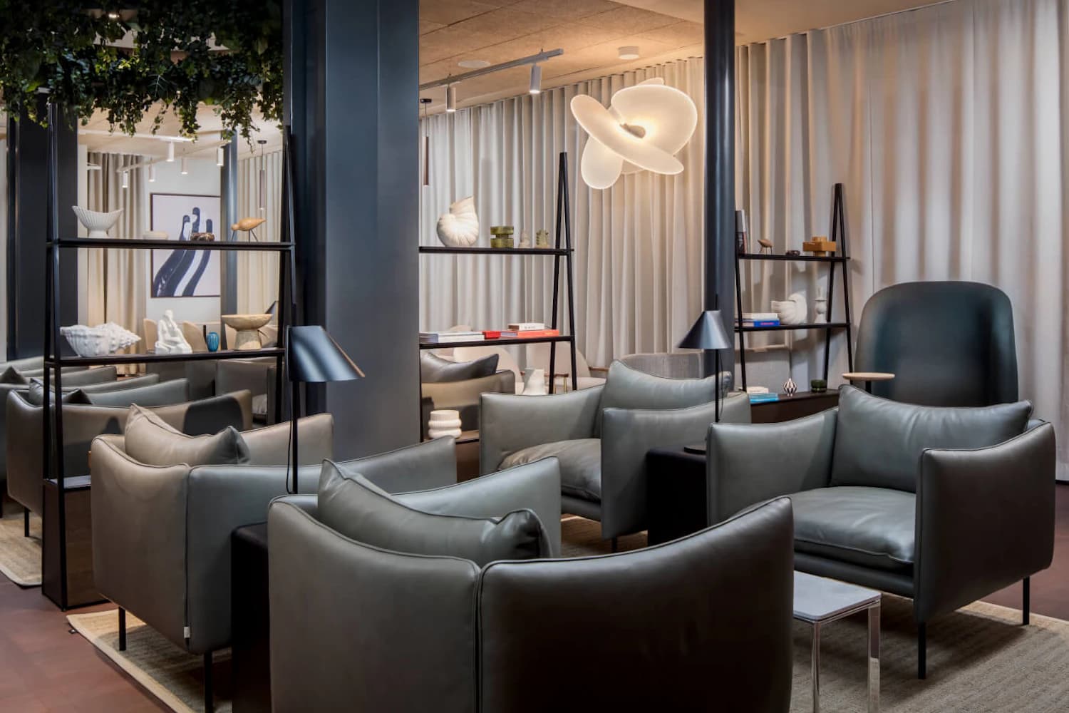 Graue Ledersessel, offene Regale und Hängeleuchte in der Aspire Lounge Terminal 2 am Flughafen Kopenhagen