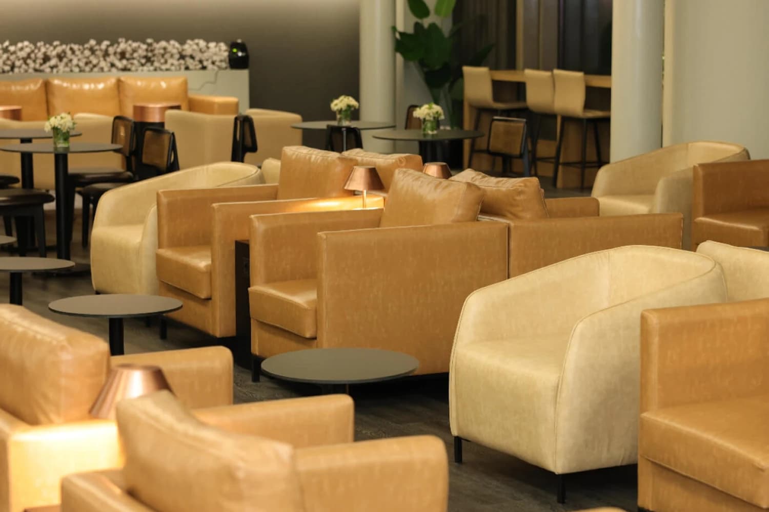 Beige und braune Ledersessel mit niedrigen runden Tischen in der Celebi International Platinum Lounge am Flughafen Adana