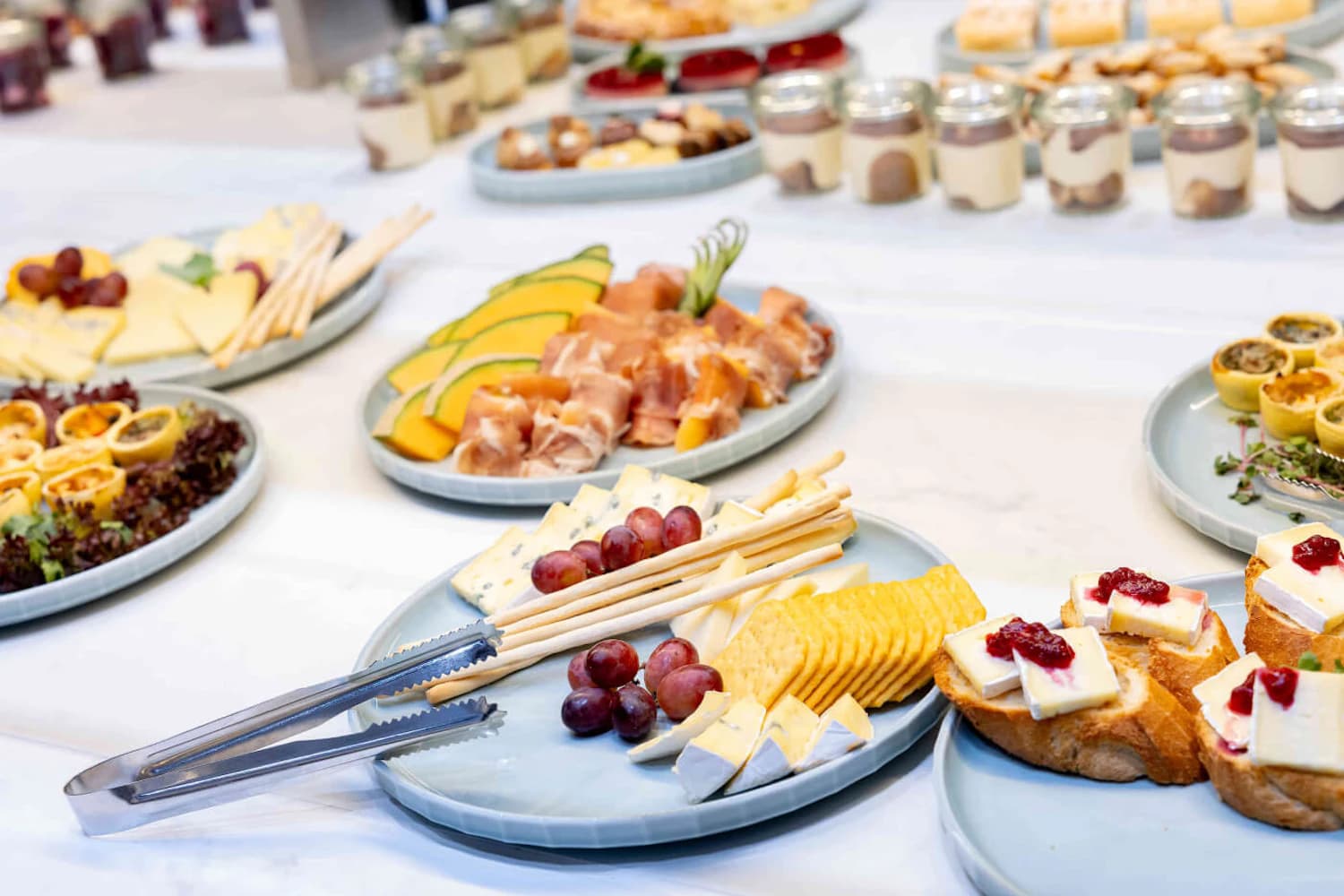Platten mit Käse, Trauben, Stangengebäck, Crackern, Schinken und Brot mit Käse und Gelee.