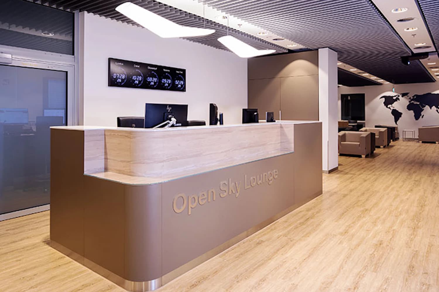 Rezeptionstresen mit Schriftzug Open Sky Lounge, Computerbildschirme, Sitzbereich und Weltkarte an der Wand.