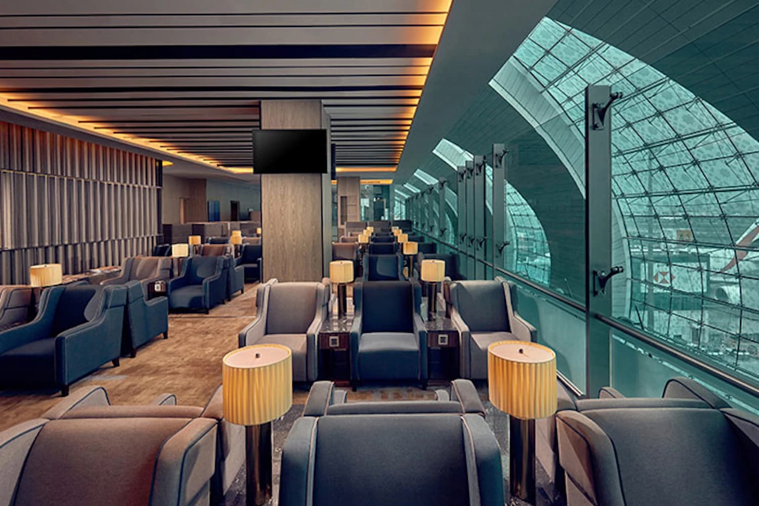 Reihen bequemer Sessel mit Tischlampen vor der großen Glasfassade der Plaza Premium Lounge in Dubai