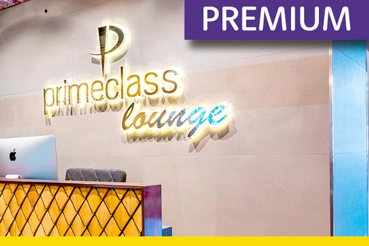 Empfangstheke mit iMac und beleuchtetem Schriftzug primeclass lounge an heller Wand.