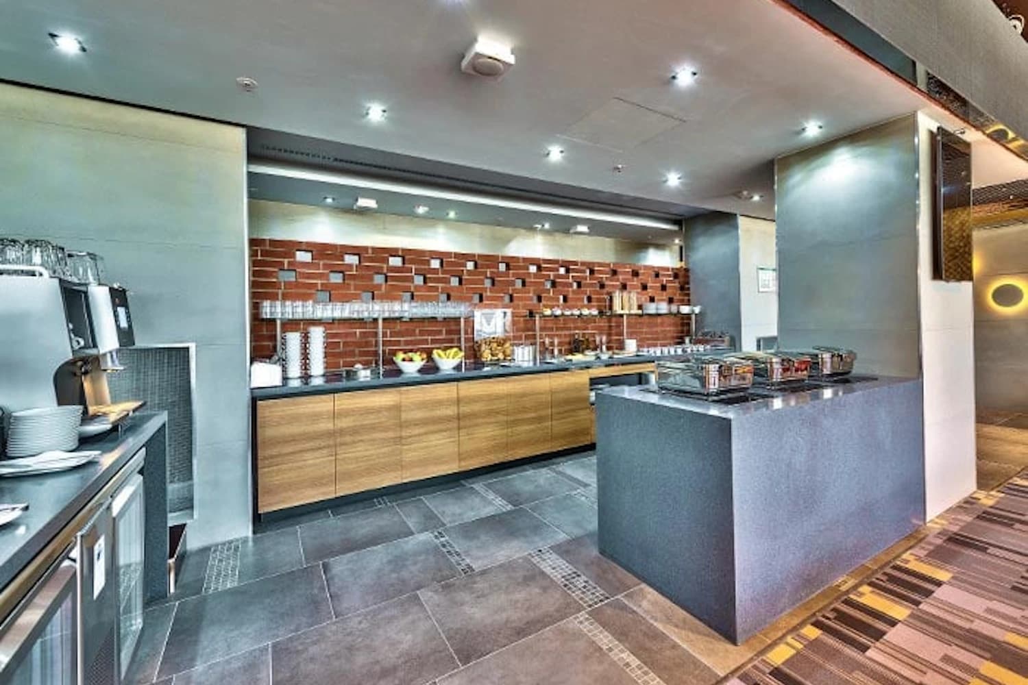 Buffetinsel mit Speisen, Kaffeemaschine und Selbstbedienungsstation in der Primeclass Lounge am Flughafen Frankfurt