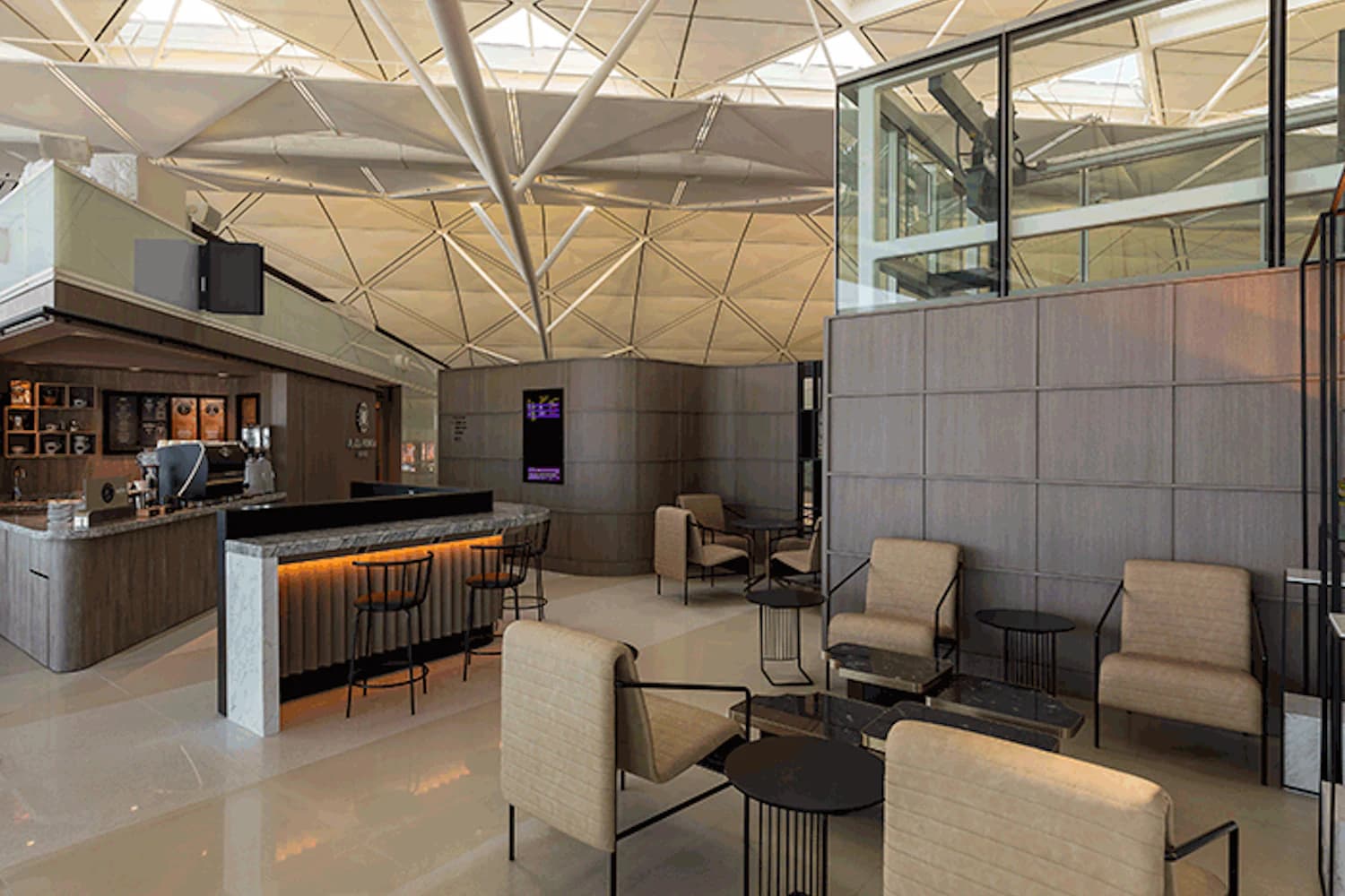 Helle Sitzgruppen mit Beistelltischen unter der geometrischen Decke der Plaza Premium Lounge Gate 60 am Flughafen Hongkong