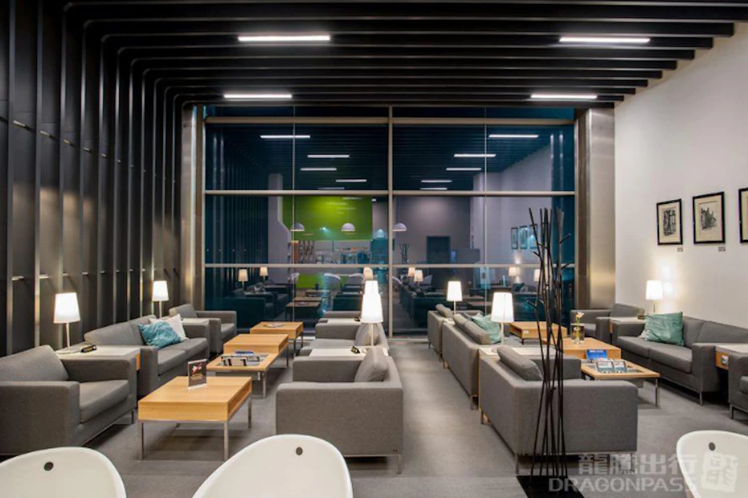 Graue Sofas, Holztische und Stehlampen vor der Fensterfront der Business Lounge am Flughafen Krakau