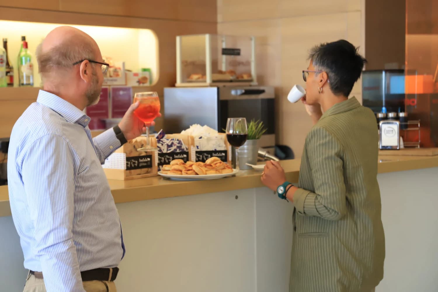 Zwei Gäste an der Theke mit Gebäck und Gläsern in der Piemonte Lounge am Flughafen Turin